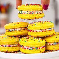 image of funfetti macarons being stacked on a plate that have been decorated with colorful nonpareil sprinkles