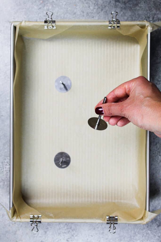 image of sheet cake pan with flower nails being used as heating cores to help the cake bake more quickly and evenly