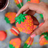 image of a strawberry shaped french macaron held up to show it's adorable shape