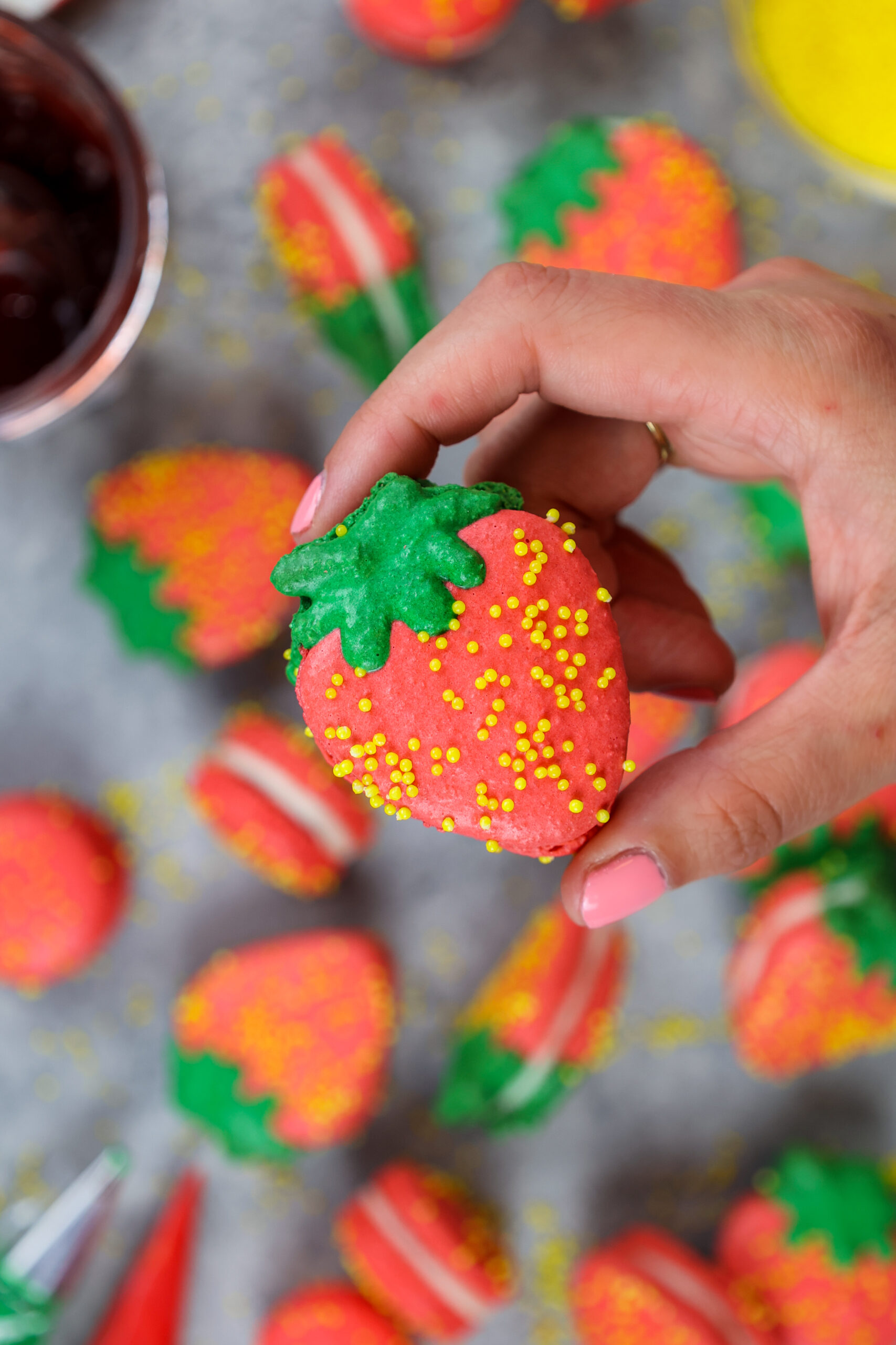 image of a strawberry shaped french macaron held up to show it's adorable shape