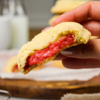 image of raspberry cheesecake cookies that have been bit into to show their raspberry cheesecake filling