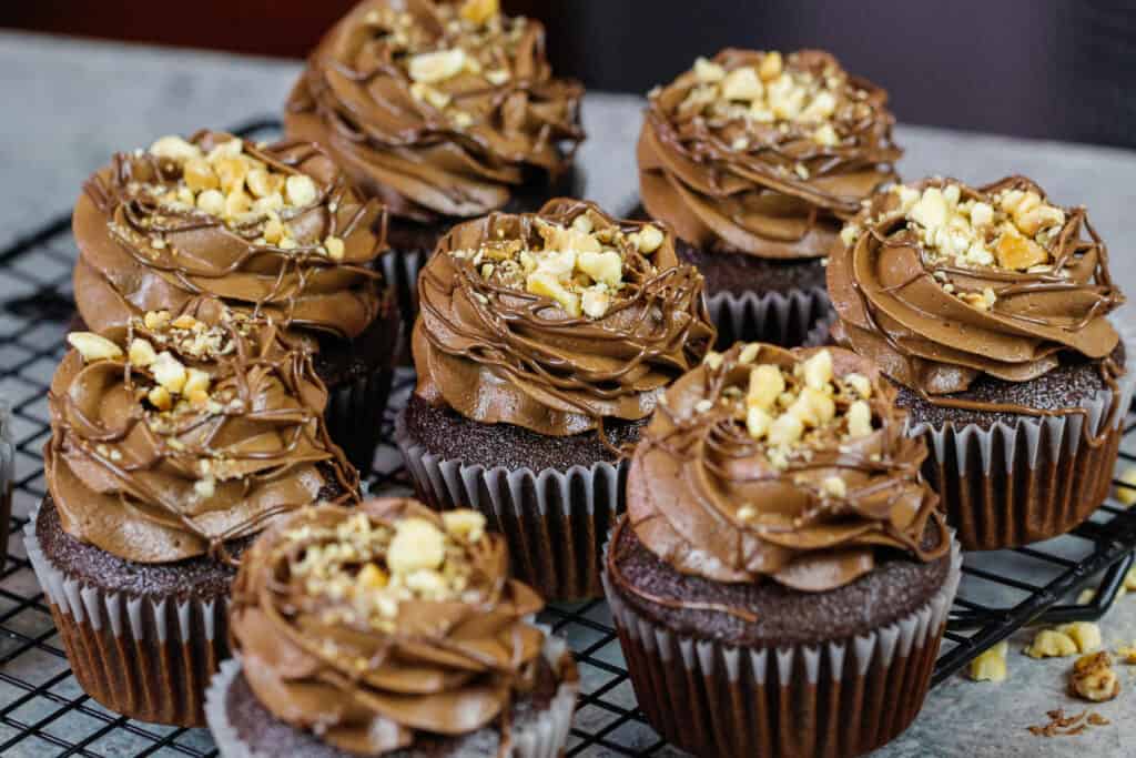 image of chocolate nutella cupcakes decorated with a nutella drizzle and toasted hazelnuts