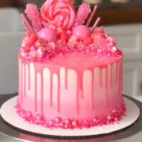 image of pretty pink drip cake decorated with candy for girls birthday party