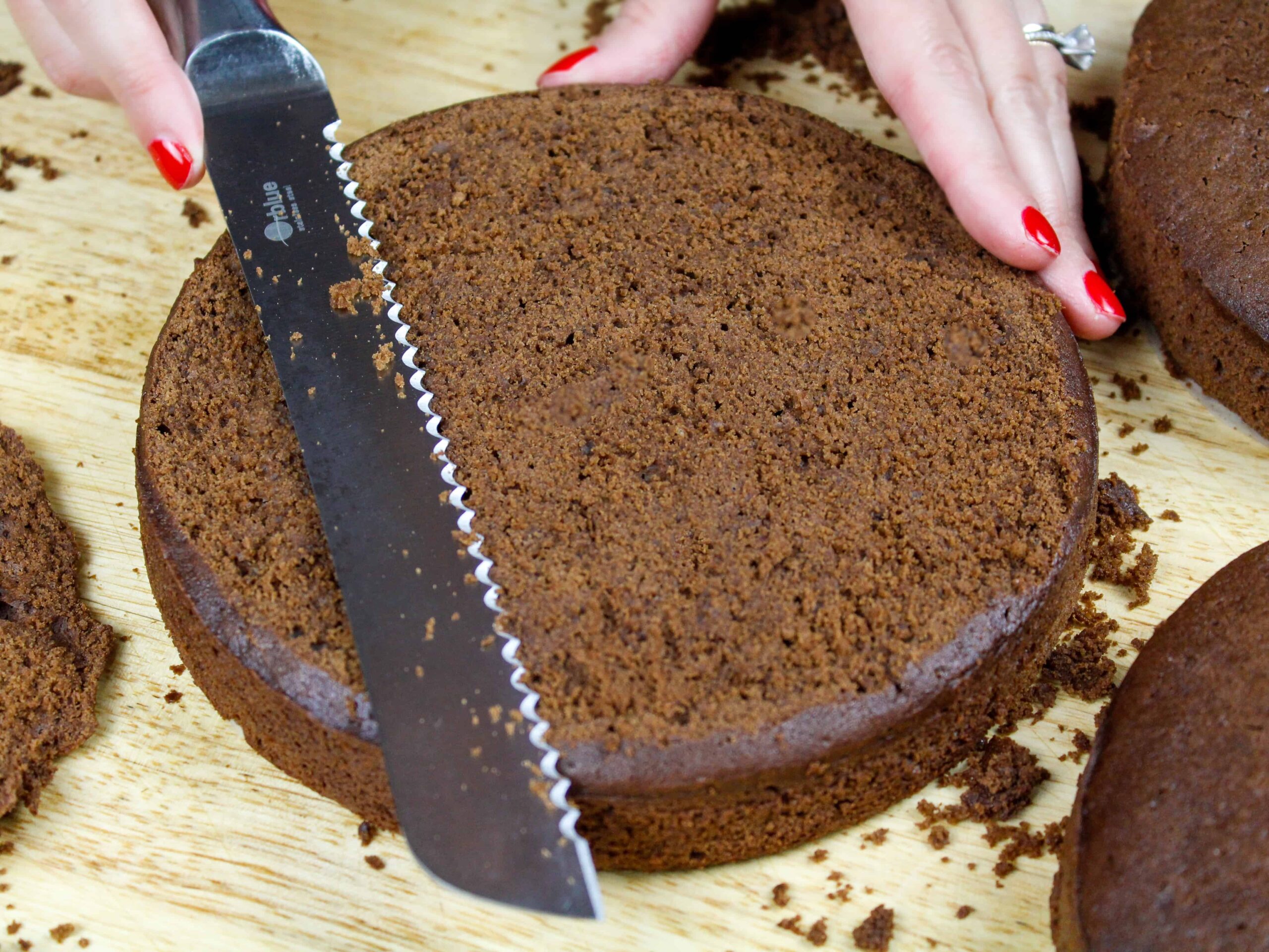 image of chocolate cake layers being leveled with a serrated knife