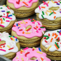 image of donut macarons decorated with royal icing to look just like little frosted sprinkle donuts