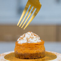 image of a mini pumpkin cheesecake topped with whipped cream and a dusting of cinnamon