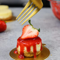 image of a mini strawberry cheesecake topped with a fresh strawberry garnish