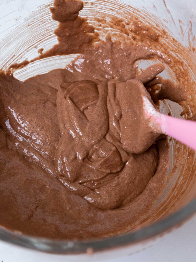 image of dark chocolate macaron batter that's been folded the perfect amount and has passed the figure 8 test