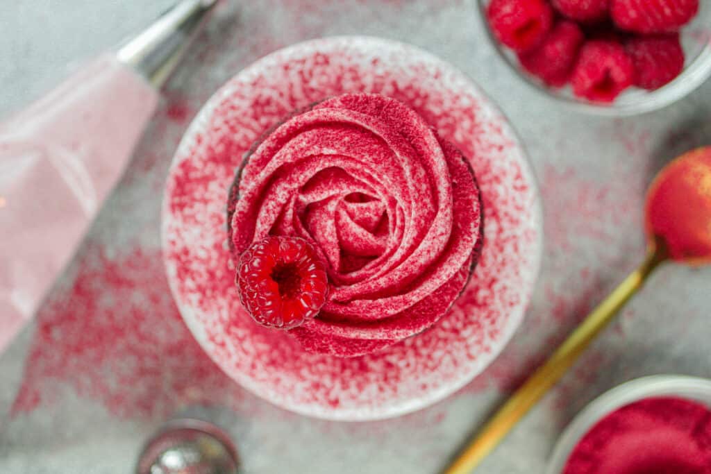 image of chocolate cupcake with raspberry frosting piped into a rosette on top of it
