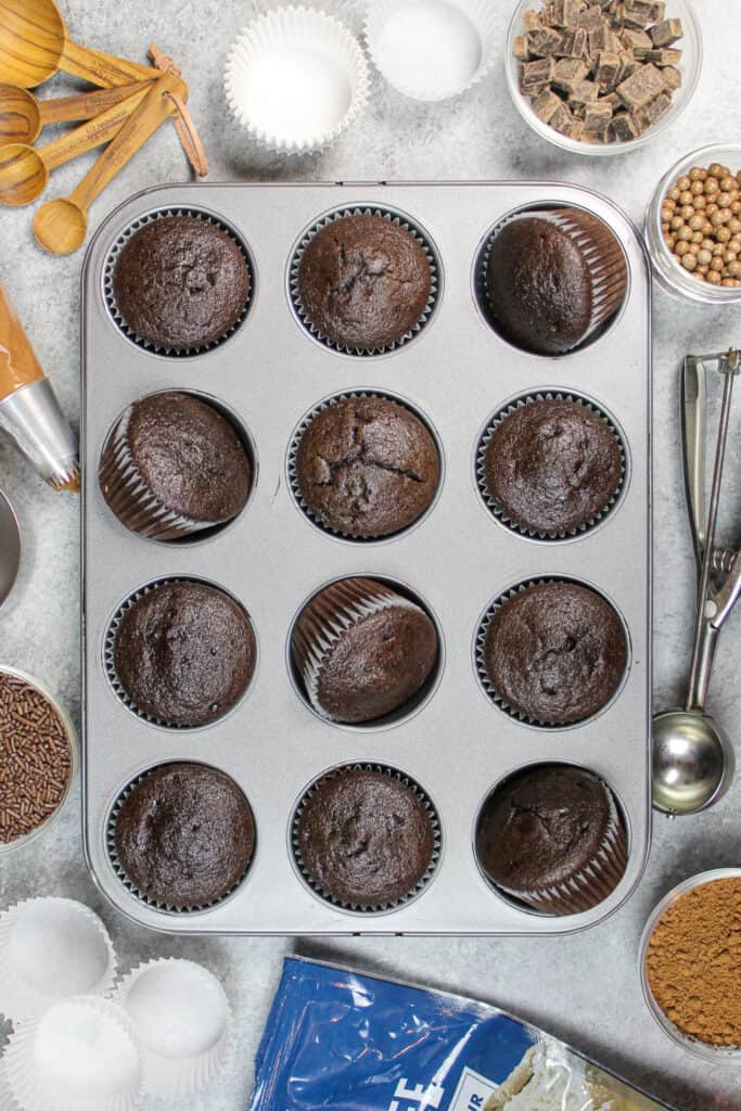 image of gluten free cupcakes in the baking pan, surrounded by ingredients and frosting
