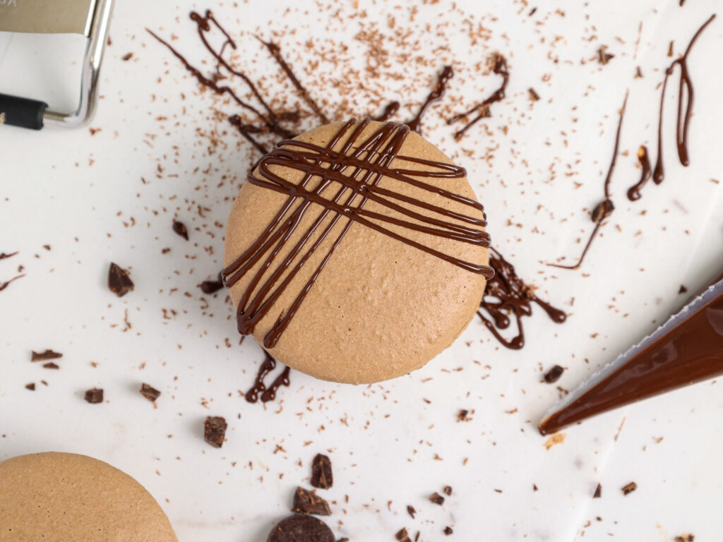 image of a chocolate macaron that's been drizzled with melted chocolate to decorate the top of it