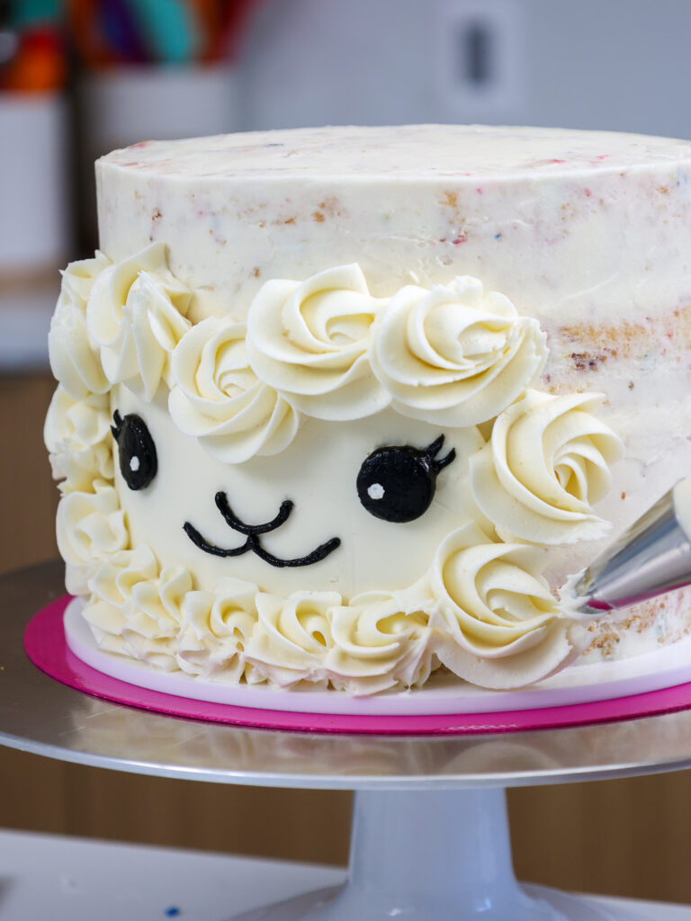 image of white buttercream being piped around a llama cake