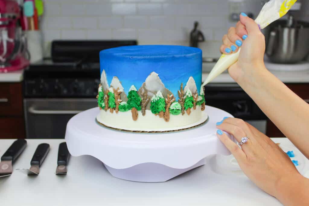 image of piping snow onto winter landscape cake