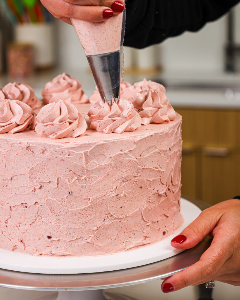 image of a cake that's being frosted with a strawberry swiss meringue buttercream frosting