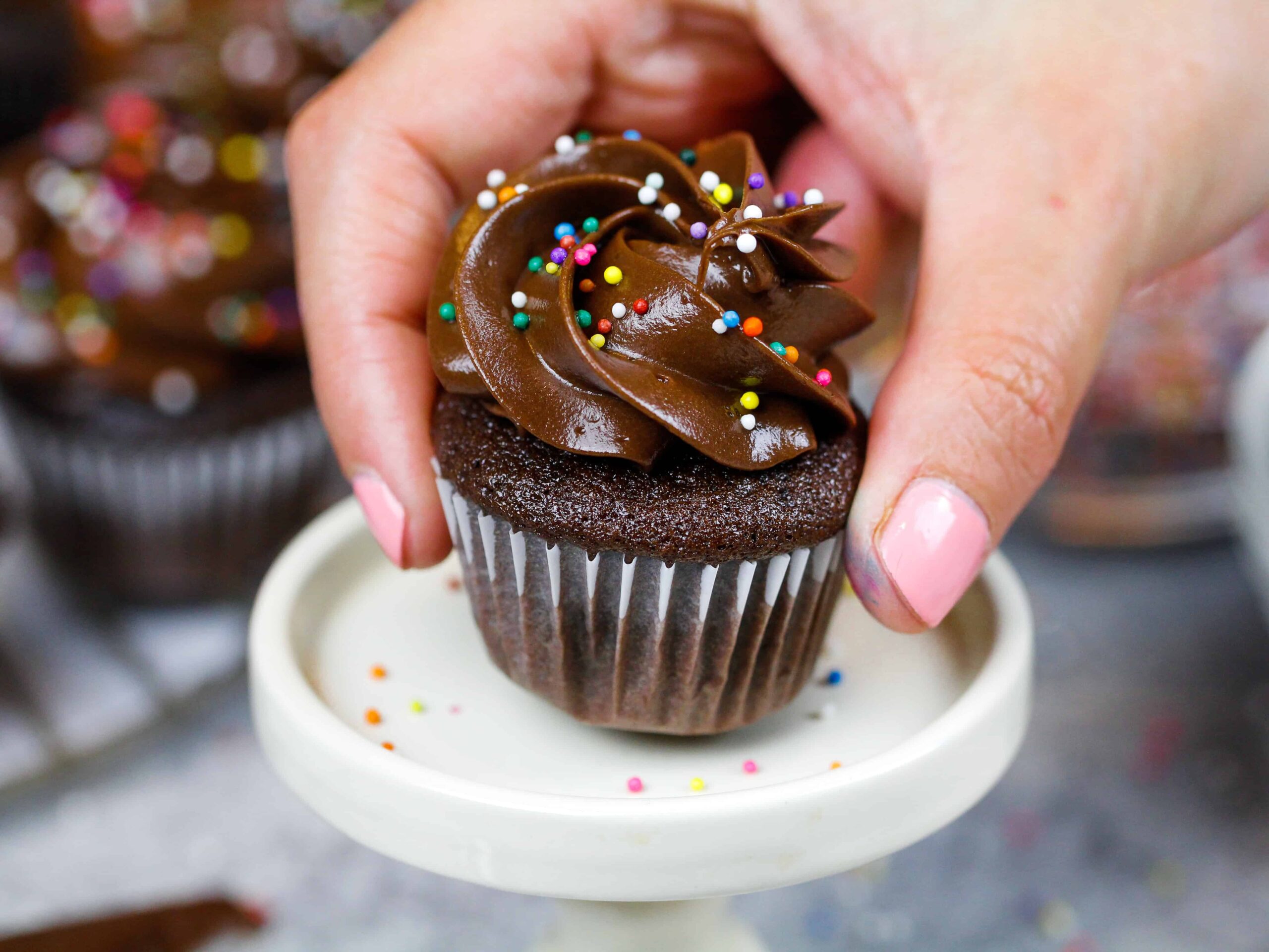 image of a mini chocolate cupcake being placed on a mini cake stand