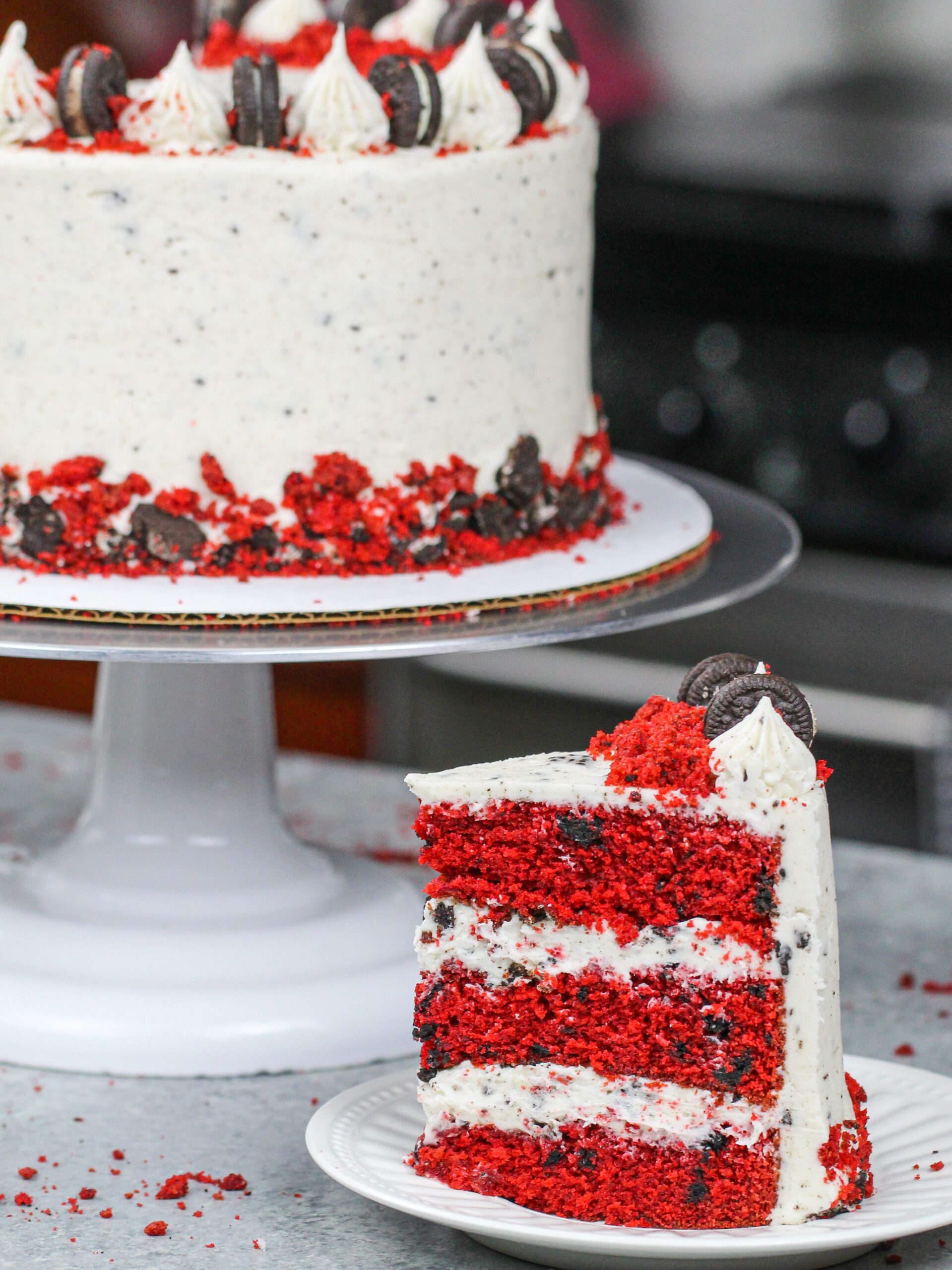 image of a red velvet oreo cake slice placed on a plate in front of the full cake