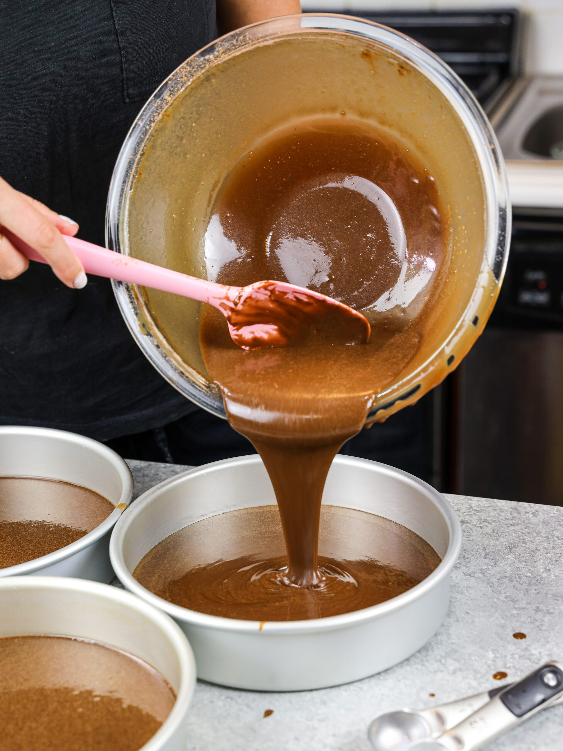 image of my moist chocolate cake batter being poured into 8 inch cake pans