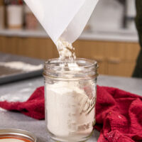 image of heat treated flour being poured into a mason jar for storage for future use