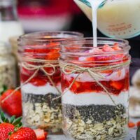 image of milk being poured into a mason jar filled with ingredients to make strawberry overnight oats