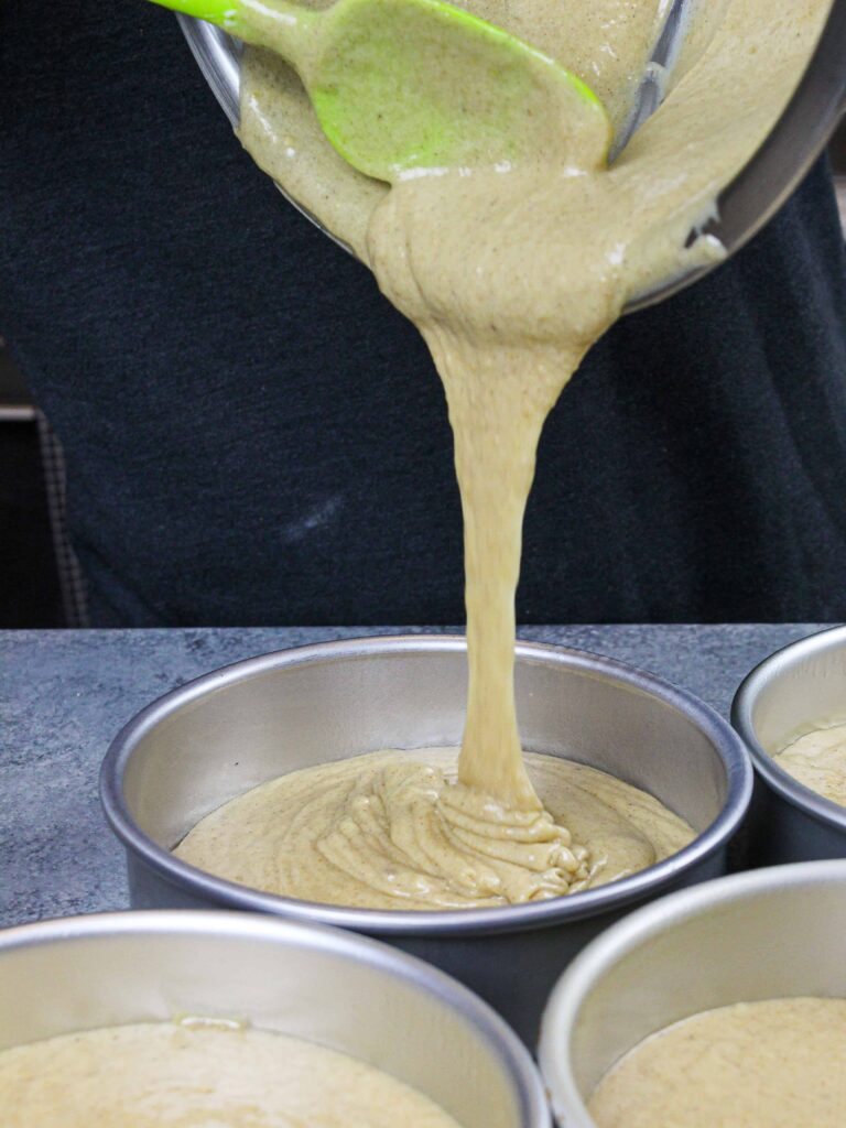 image of spice cake batter being poured into cake pans to make a layered spice cake