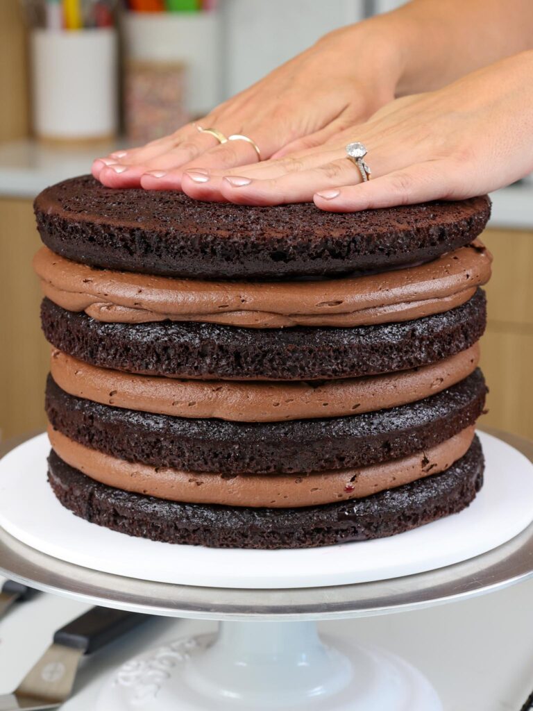 image of dark chocolate cake layers being stacked with dark chocolate buttercream