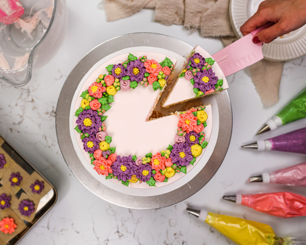 image of a buttercream flower cake that's been decorate with pink, purple and yellow buttercream flowers