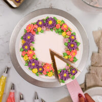 image of a buttercream flower cake that's been decorate with pink, purple and yellow buttercream flowers