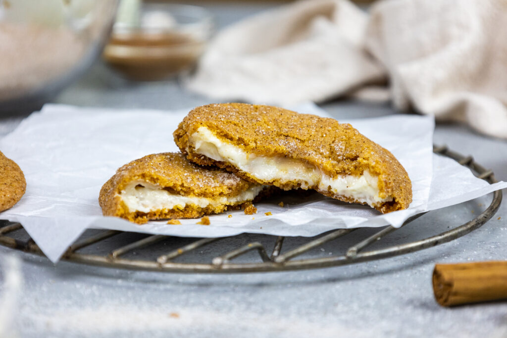 image of a pumpkin cheesecake cookie that's been broken open to show its cheesecake filling