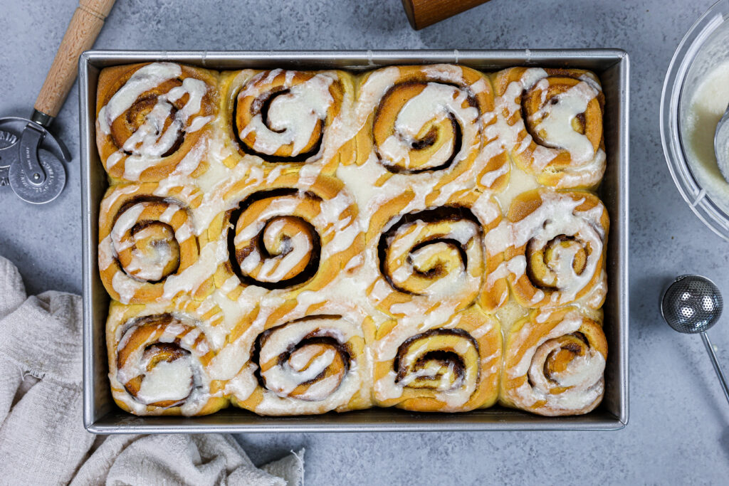 image of pumpkin pie cinnamon rolls that have been baked and glazed with vanilla cinnamon roll glaze