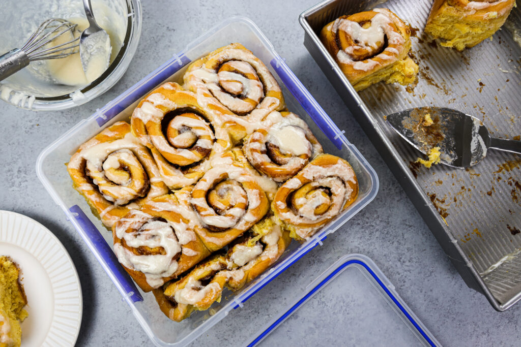 image of pumpkin pie cinnamon rolls that have been place in an airtight container to be frozen and eaten later