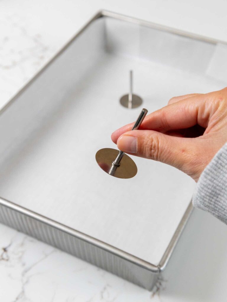 image of a quarter sheet pan with flower nails or heating cores being put into place before being filled with batter