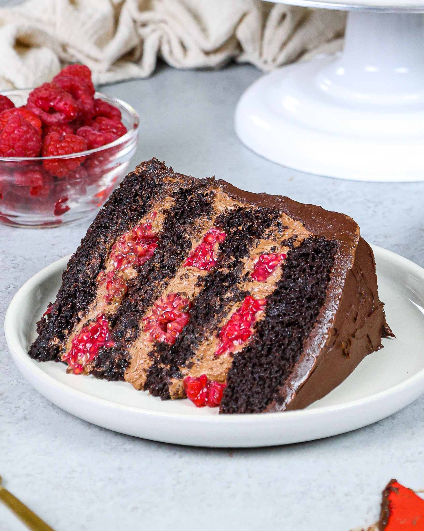 image of a chocolate raspberry mousse cake made with chocolate mousse, chocolate cake layers, raspberry jam and fresh raspberries