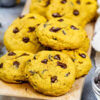 image of vegan pumpkin chocolate chip cookies stacked on a board ready to be eaten