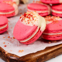 image of strawberry shortcake macarons that have been filled with strawberry jam and a mascarpone filling and topped with a strawberry shortcake crumble