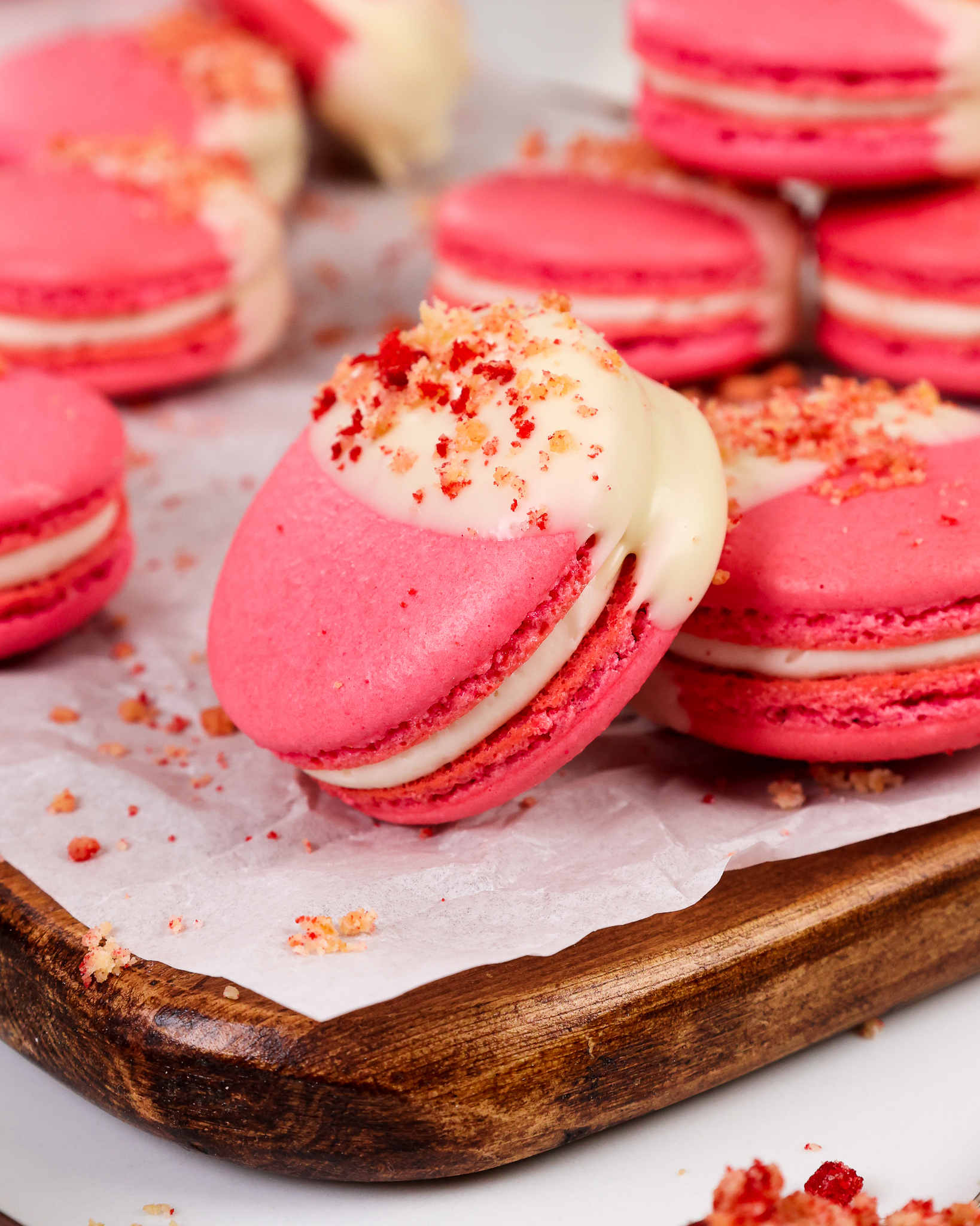 image of strawberry shortcake macarons that have been filled with strawberry jam and a mascarpone filling and topped with a strawberry shortcake crumble