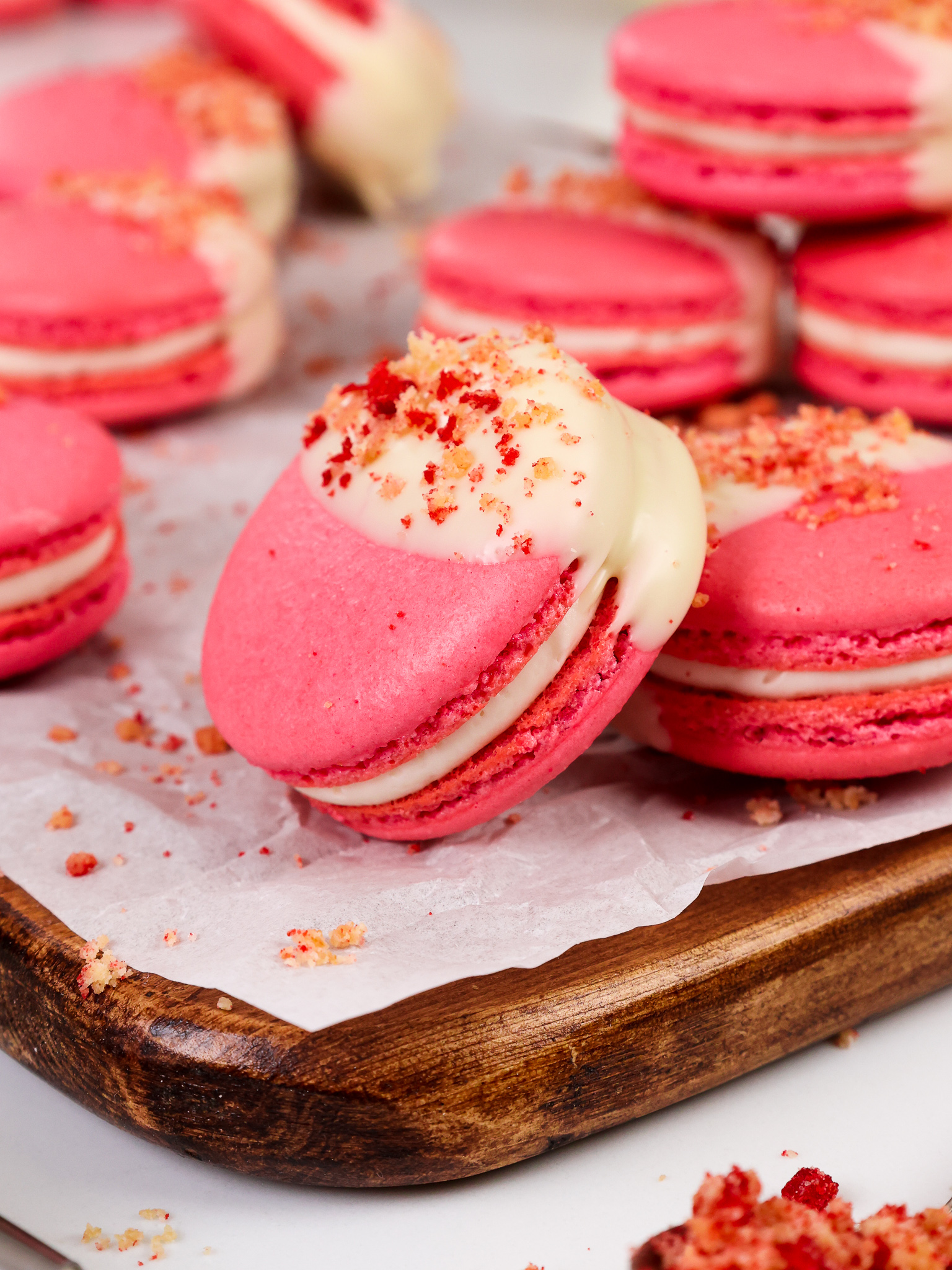 image of strawberry shortcake macarons that have been filled with strawberry jam and a mascarpone filling and topped with a strawberry shortcake crumble