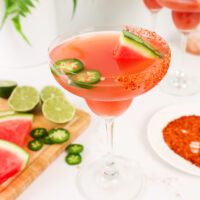 image of a jalapeno watermelon margarita in a margarita glass garnished with tajin and jalapeno slices