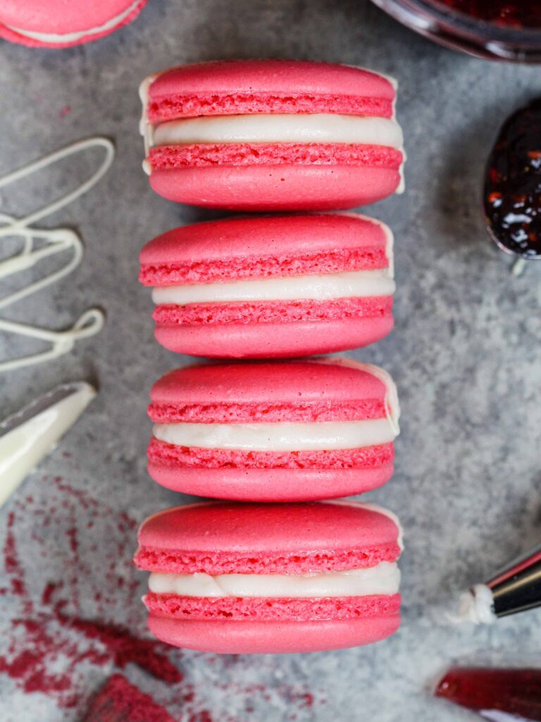 image of french raspberry macarons that have been filled with raspberry jam and buttercream and drizzled with white chocolate as a decoration