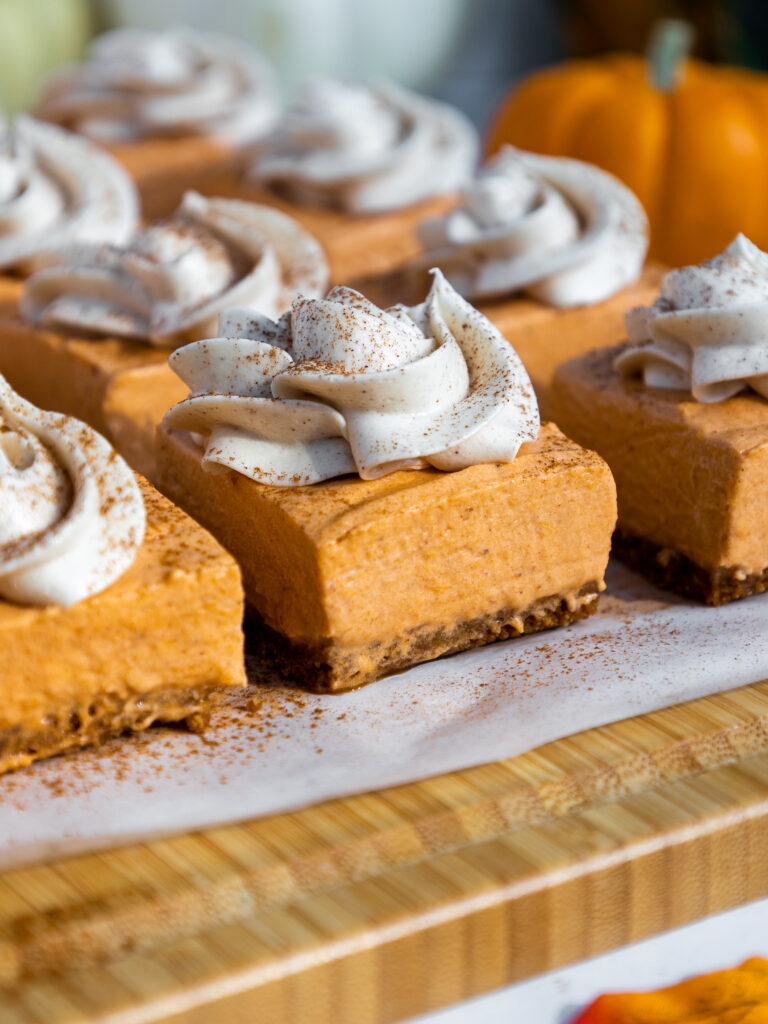 image of no bake cheesecake bars that have been cut into squares and topped with whipped cream