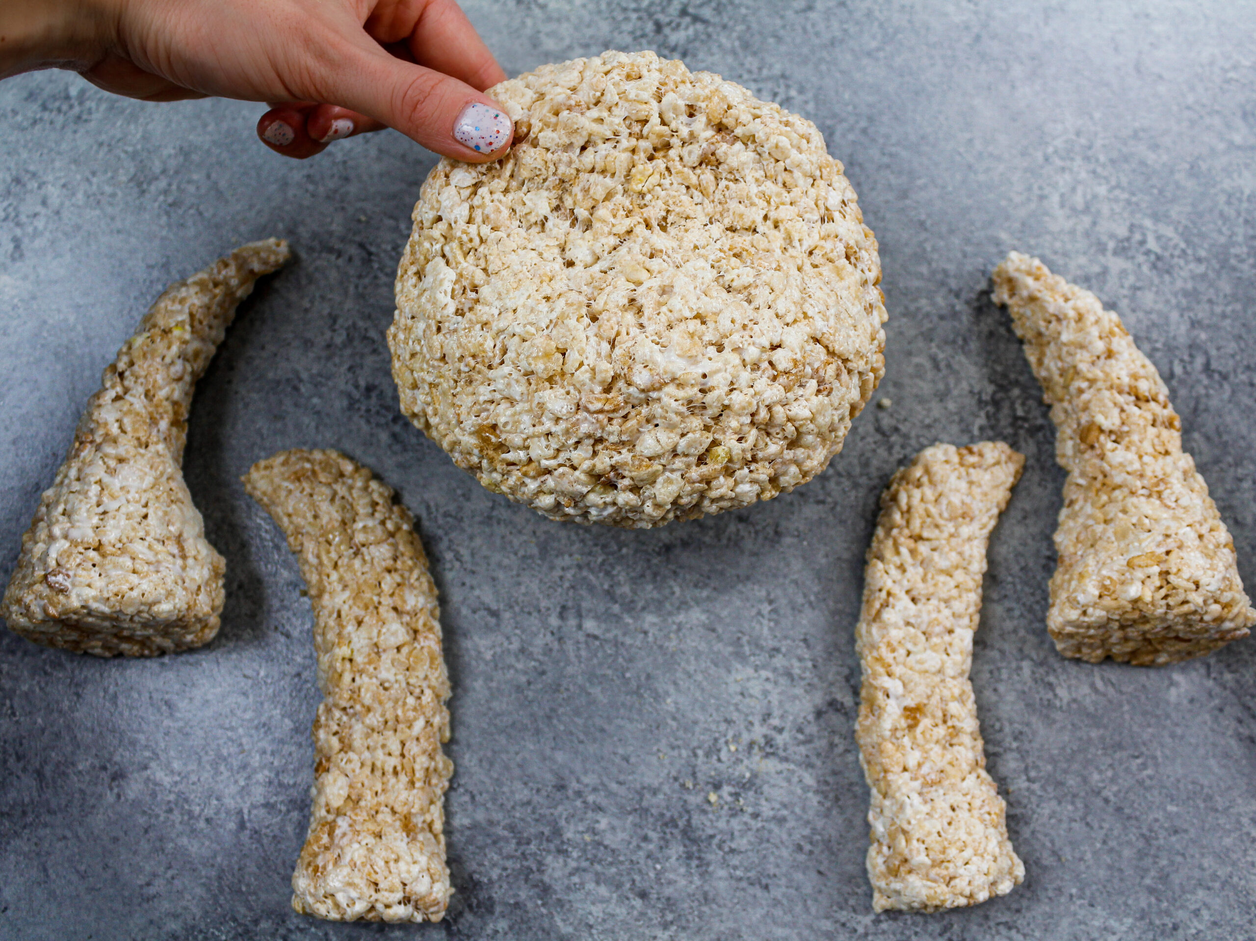image of cake decorating rice krispies that have been shaped into legs and a head to make a giraffe cake