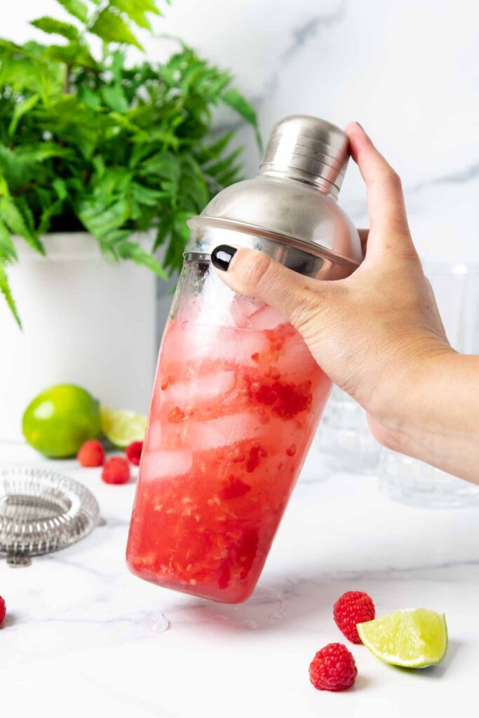 image of a glass shaker being shaken to make a raspberry floradora cocktail