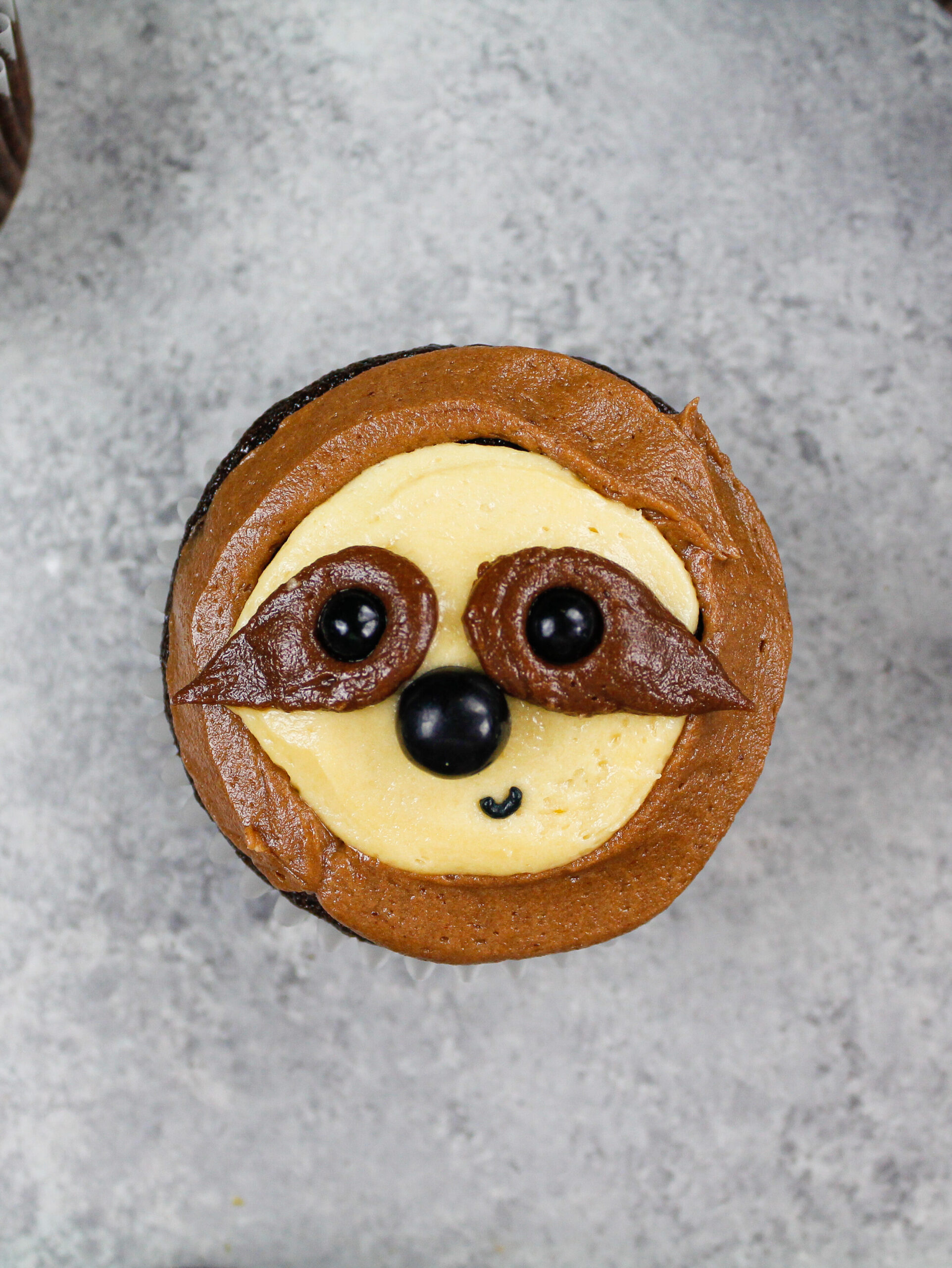 image of an adorable sloth cupcakes made with chocolate cupcake being decorated with chocolate peanut butter frosting