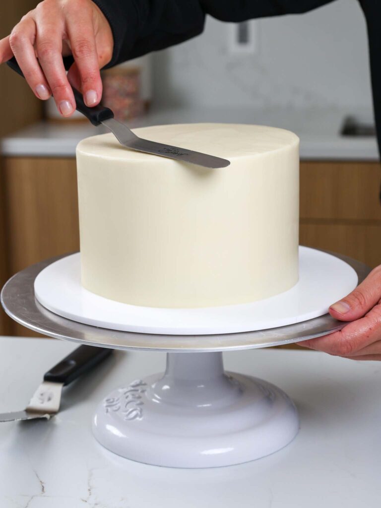 image of a cake being frosted and smoothed with an offset spatula