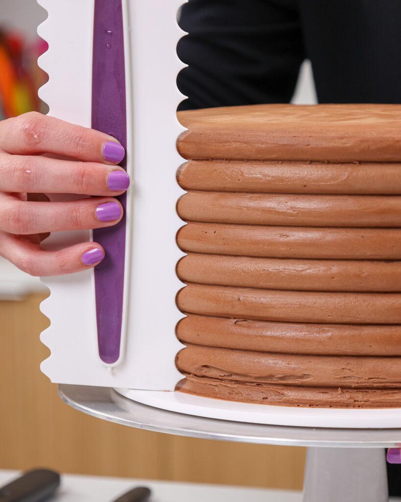 image of an icing comb being used to smooth frosting on a chocolate cake