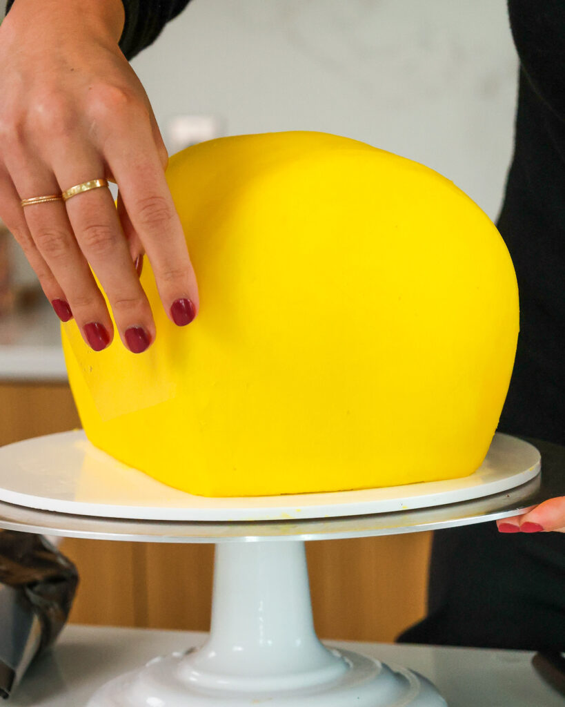 image of yellow buttercream being smoothed onto a bumblebee cake