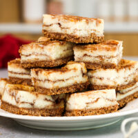 image of snickerdoodle cheesecake bars that have been cut up and stacked on a plate