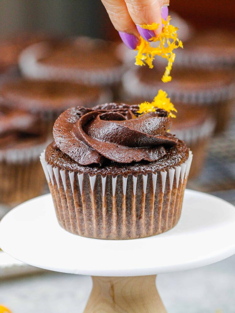 image of orange zest being added to an orange chocolate cupcake