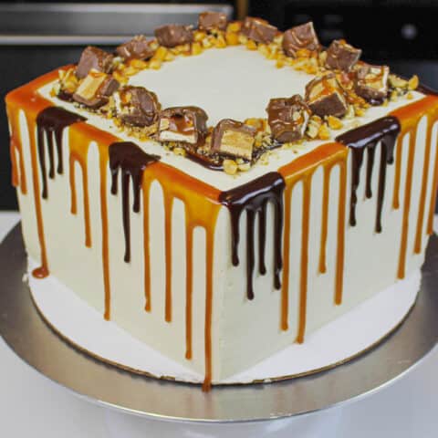 image of snickers drip cake with both a caramel and chocolate drip decoration