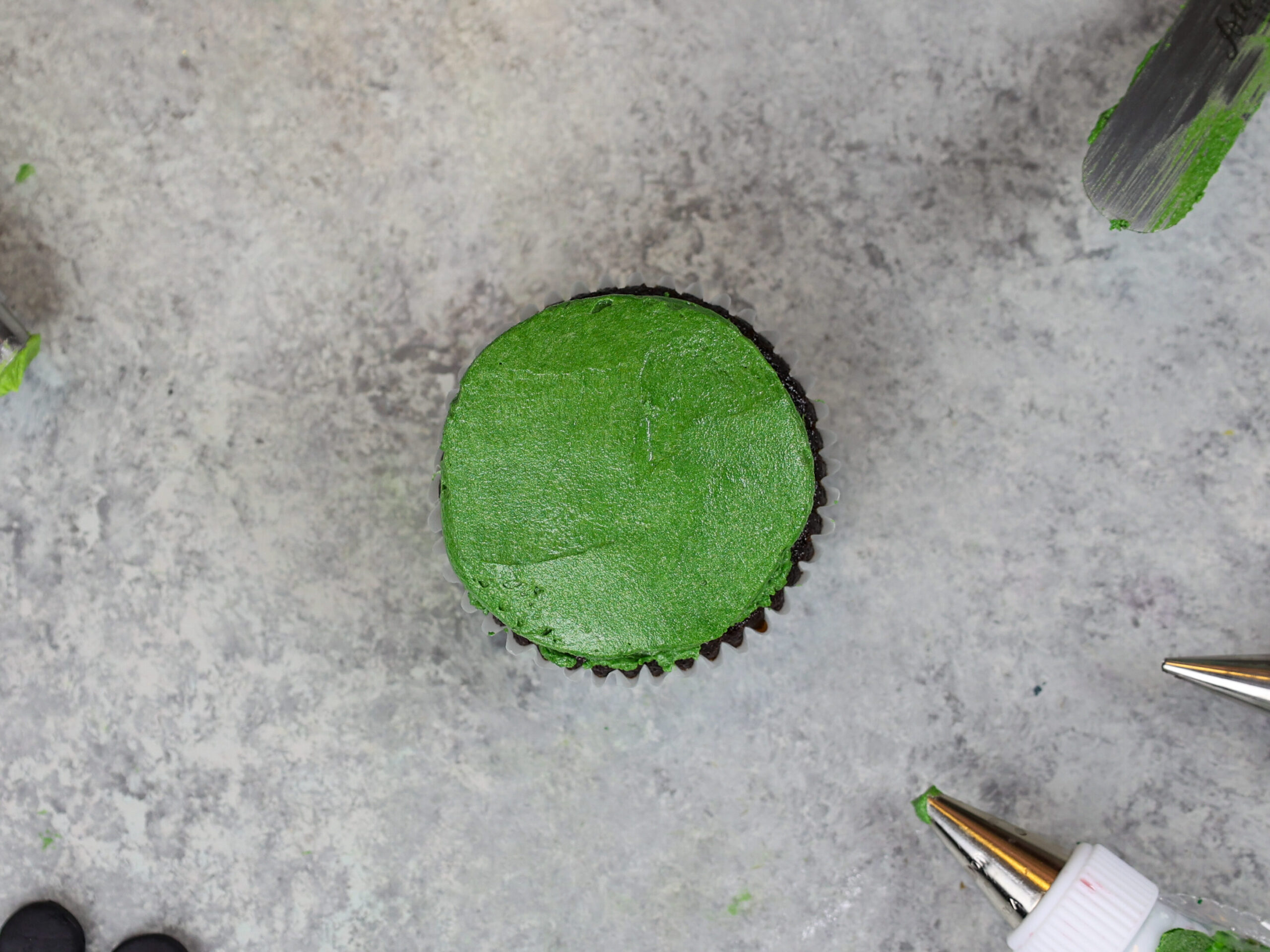 image of a frog cupcake being frosted and decorated with buttercream frosting