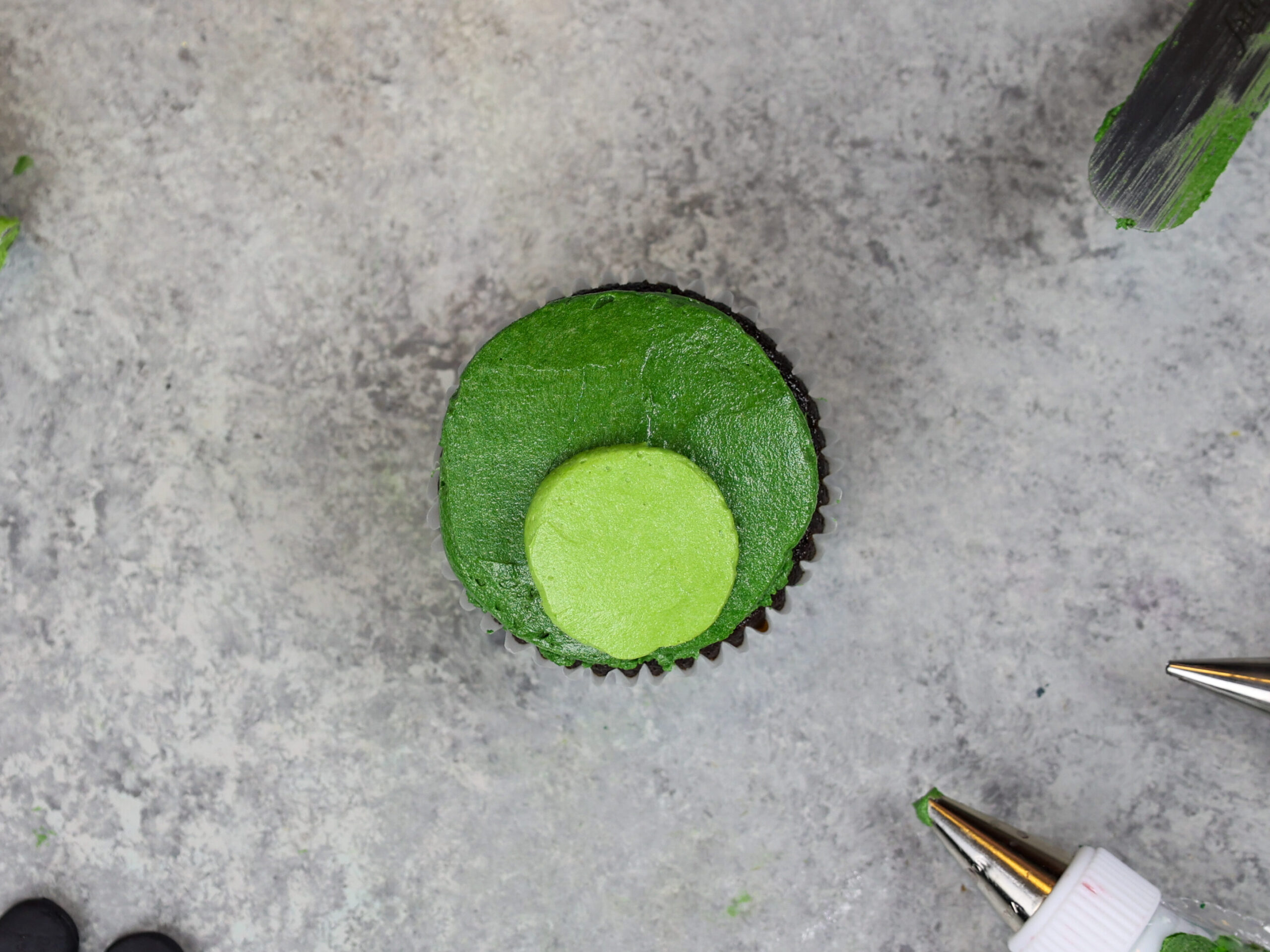 image of a frog cupcake being frosted and decorated with buttercream frosting